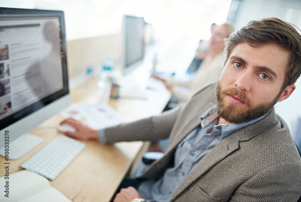 Obraz premium Portrait, graphic designer and computer with office, employee and digital agency as creative. Male person, serious and technology in typing for working, project or deadline with ambition at company