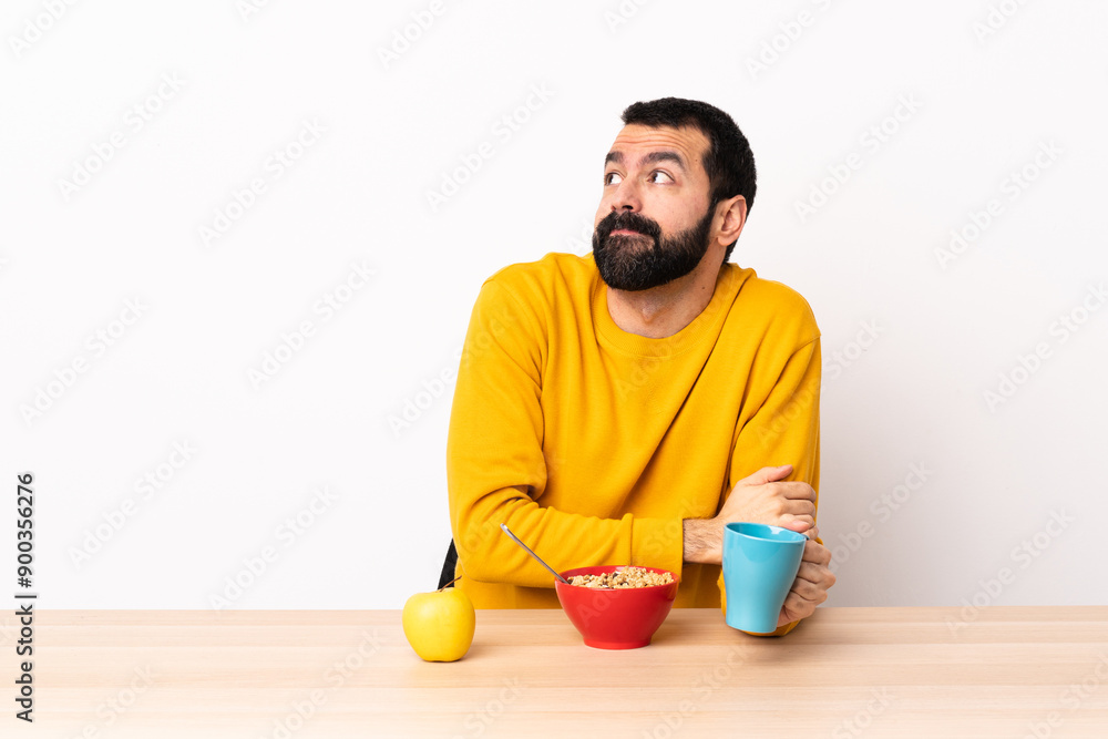 Caucasian man having breakfast in a table making doubts gesture while lifting the shoulders. Caucasian man having breakfast in a table making doubts gesture while lifting the shoulders.