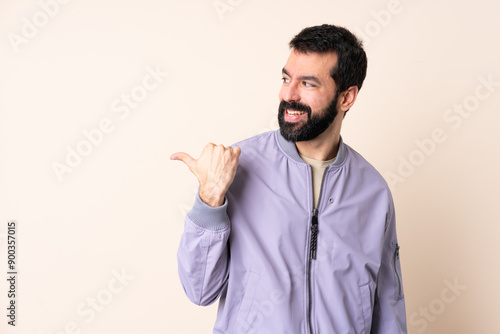 Caucasian man with beard wearing a jacket over isolated background pointing to the side to present a product