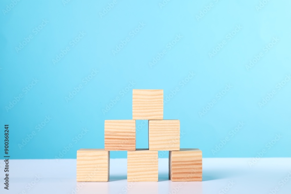 Many wooden cubes on white table against light blue background Many wooden cubes on white table against light blue background