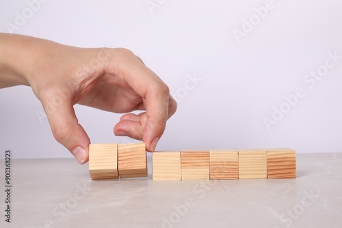 Woman with wooden cubes at light table, closeup