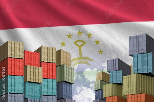 Tajikistan flag and big stack of shipping cargo containers in docks with sky background close up photo