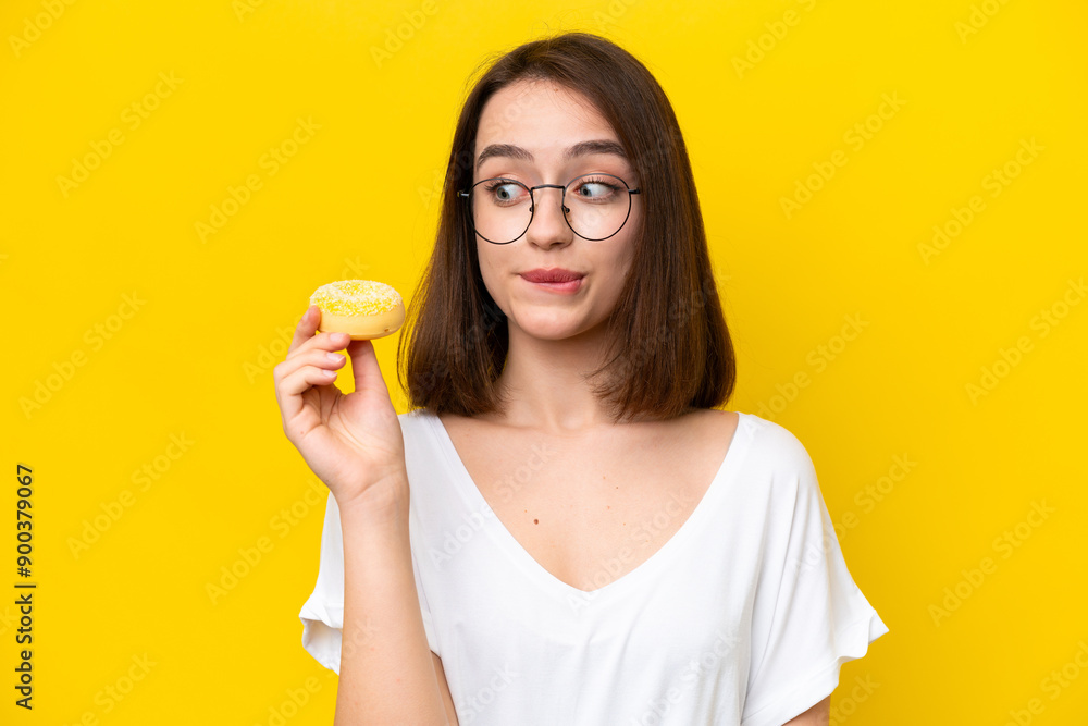 Young Ukrainian woman isolated on yellow background holding a donut Young Ukrainian woman isolated on yellow background holding a donut