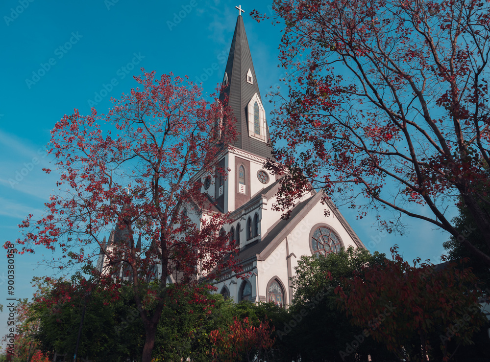 Fototapeta Charming white church with steeple surrounded by colorful autumn foliage on a cl