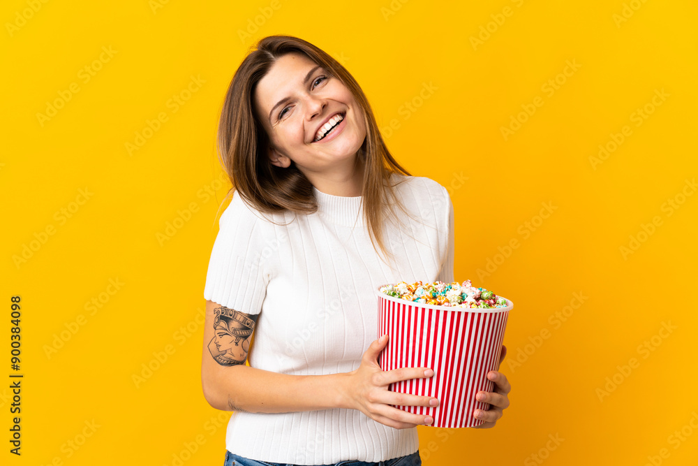 Young slovak woman isolated on yellow background holding a big bucket of popcorns Young slovak woman isolated on yellow background holding a big bucket of popcorns