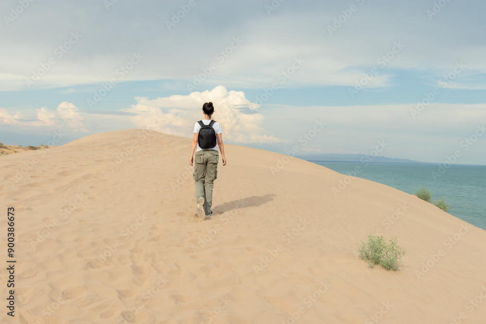 Fototapeta premium Solo Traveler Exploring Sand Dunes Overlooking Ocean: Adventure and Discovery on Coastal Desert Landscape