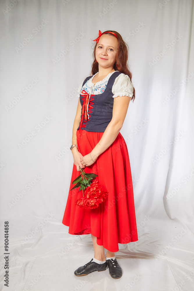 A young girl in a red dress and white blouse holds a bouquet of red roses while posing for a photo shoot A young girl in a red dress and white blouse holds a bouquet of red roses while posing for a photo shoot