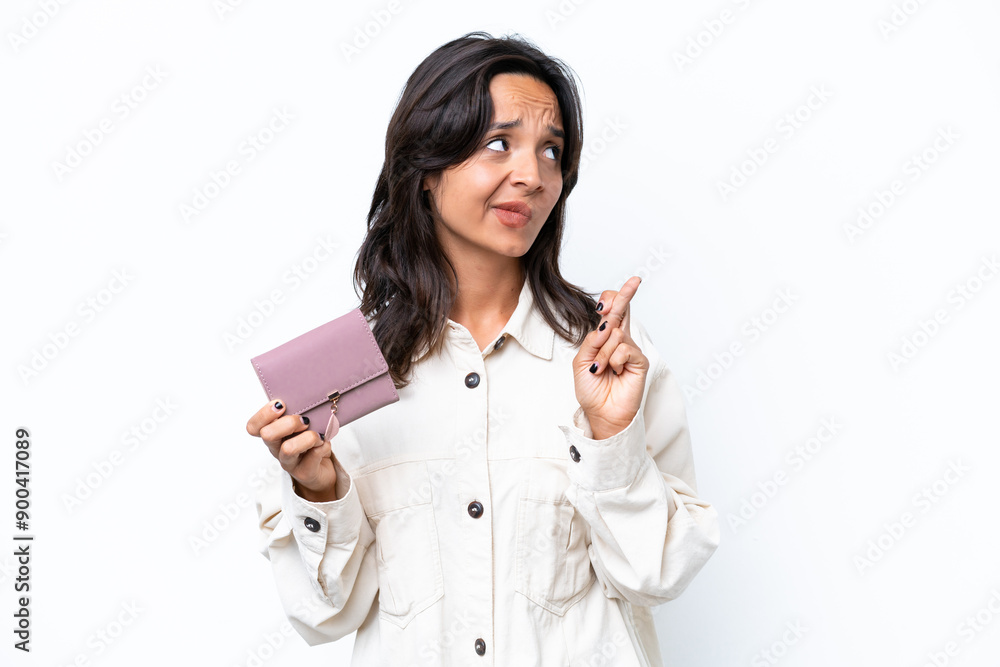 Young hispanic woman holding wallet isolated on white background with fingers crossing and wishing the best Young hispanic woman holding wallet isolated on white background with fingers crossing and wishing the best