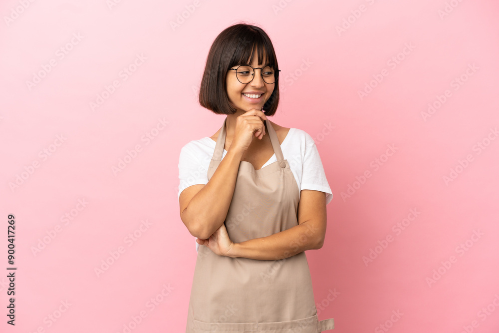 Restaurant waiter over isolated pink background looking to the side and smiling Restaurant waiter over isolated pink background looking to the side and smiling