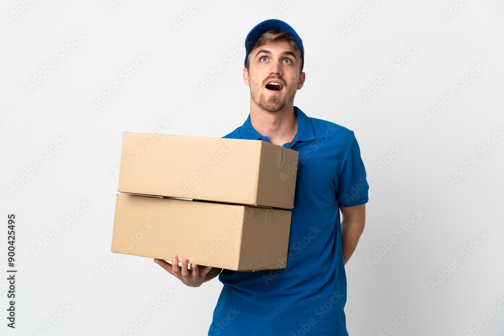 Young delivery blonde man isolated on white background looking up and with surprised expression Young delivery blonde man isolated on white background looking up and with surprised expression