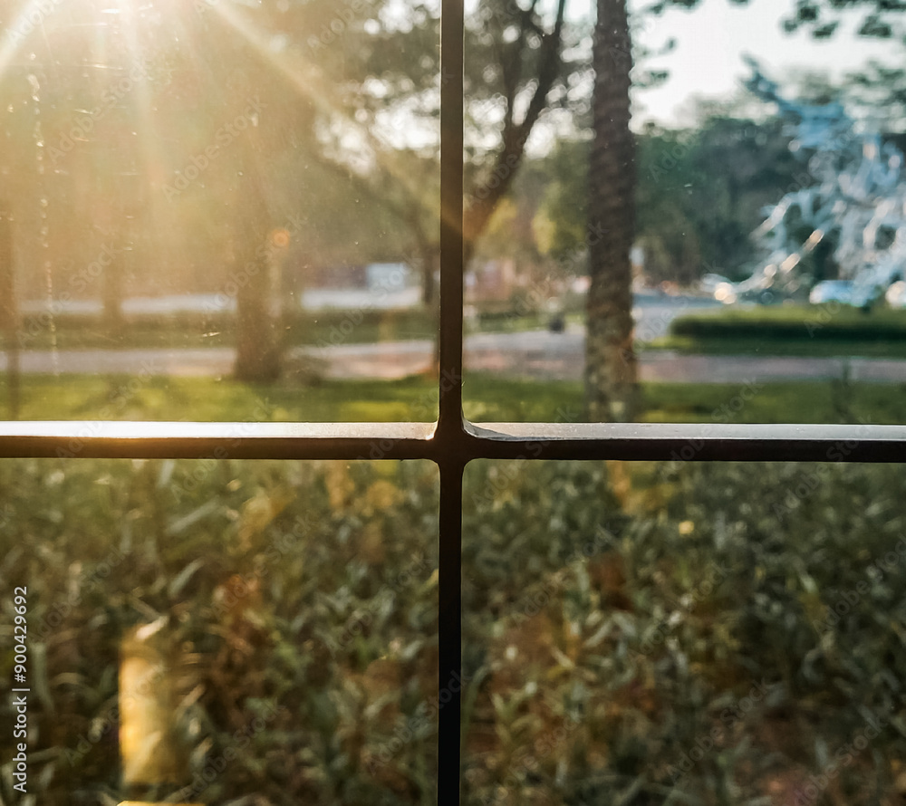 Golden evening sunlight peeks through and streams in through a glass window Golden evening sunlight peeks through and streams in through a glass window