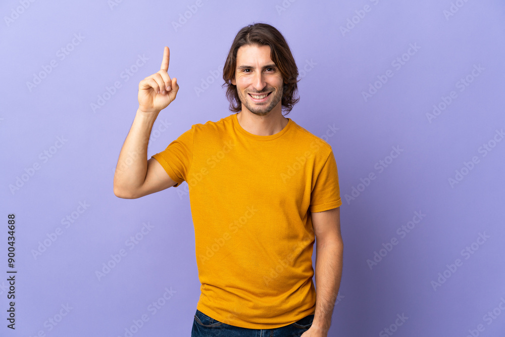 Young handsome man isolated on purple background pointing up a great idea Young handsome man isolated on purple background pointing up a great idea