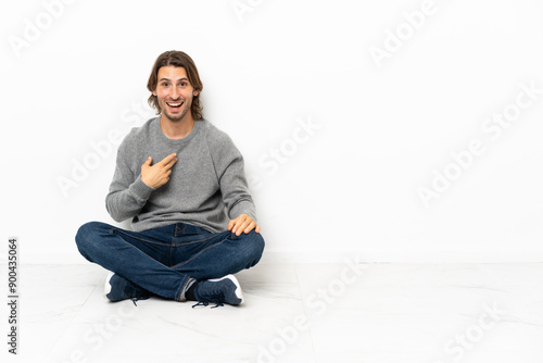 Young handsome man sitting on the floor over isolated background with surprise facial expression © luismolinero