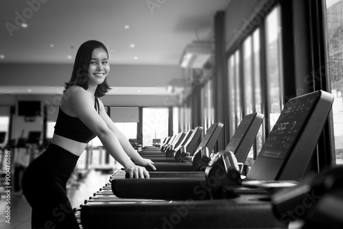 Obraz na płótnie black and white photo portrait of a young woman exercise in gym, running use thereadmill machine equipment, healthy lifestyle, cardio exercise in fitness club concepts. w salonie