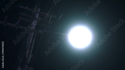 Lone streetlight flickers ominously, casting eerie shadows on deserted road.