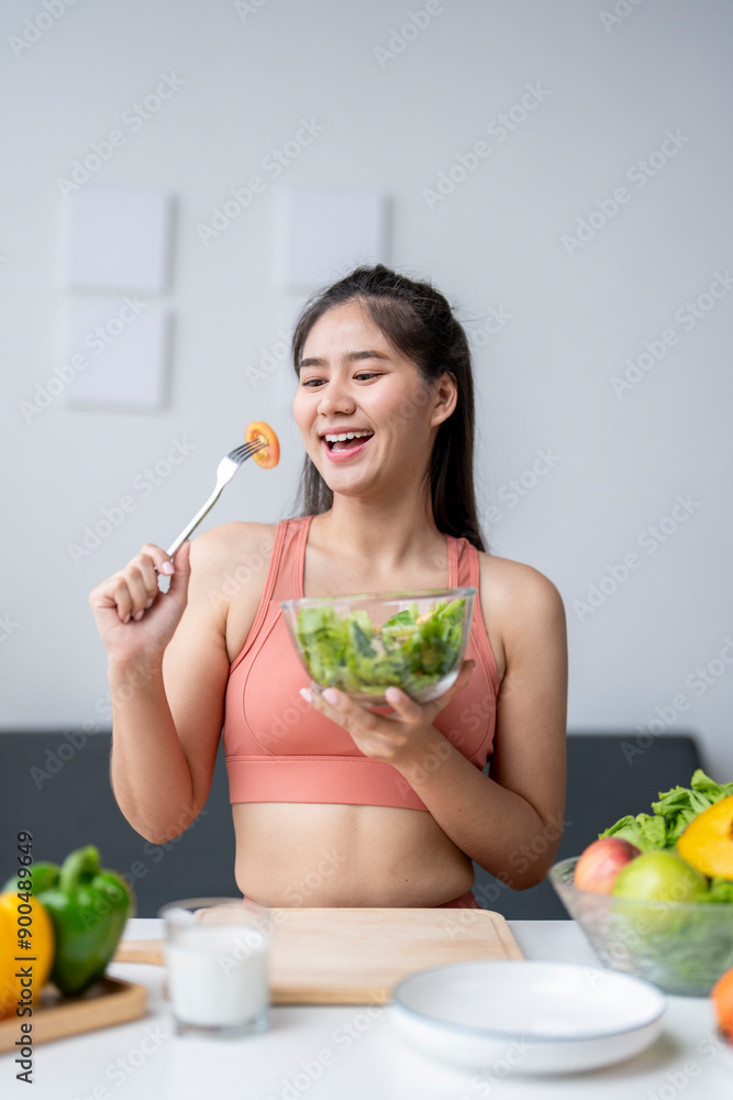 Young asian woman enjoying a healthy salad at home after workout Young asian woman enjoying a healthy salad at home after workout