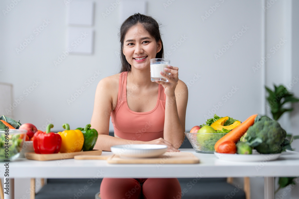 Young woman drinking milk surrounded by fresh fruits and vegetables Young woman drinking milk surrounded by fresh fruits and vegetables