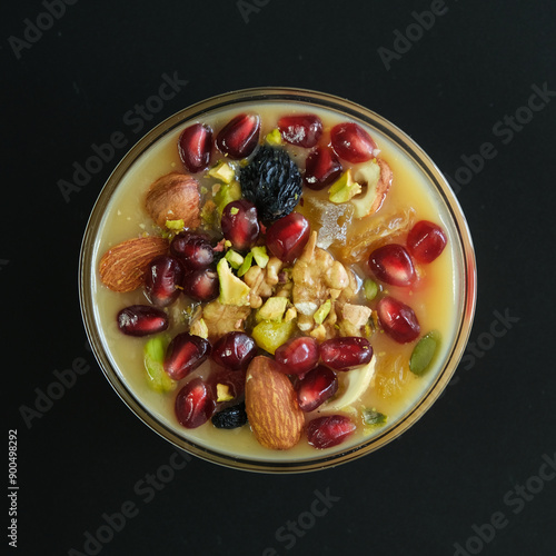 Ashure Dessert, Ashura or Anusabur on dark table. Turkish delicious porridge with grains, nuts and fruits. Sweet pudding also called as Noah's pudding or Noah's Dessert. photo