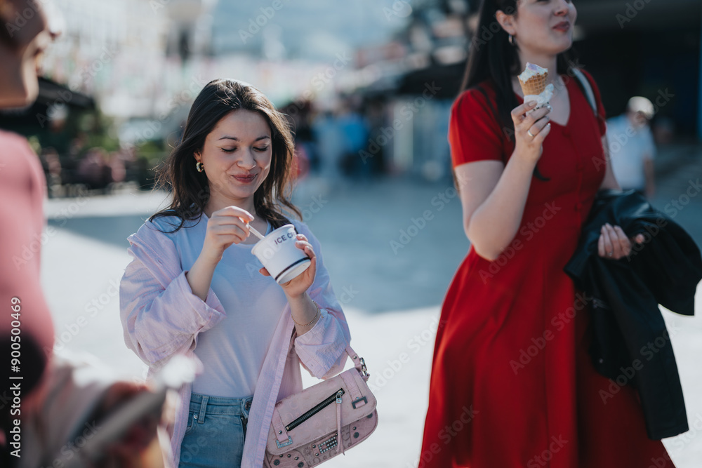 Fototapeta premium Young, fashionable women share a moment of joy while eating ice cream in the city, celebrating their free time.
