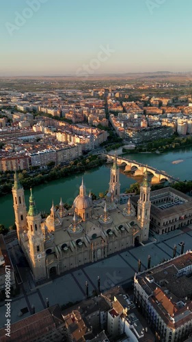 Spectacular 4K aerial view of city center of ZARAGOZA, Spain. View of Zaragoza Cathedral, River Ebro and Stone Bridge in background. Beautiful warm colours at sunset. Drone backwards. Travel. Vertical