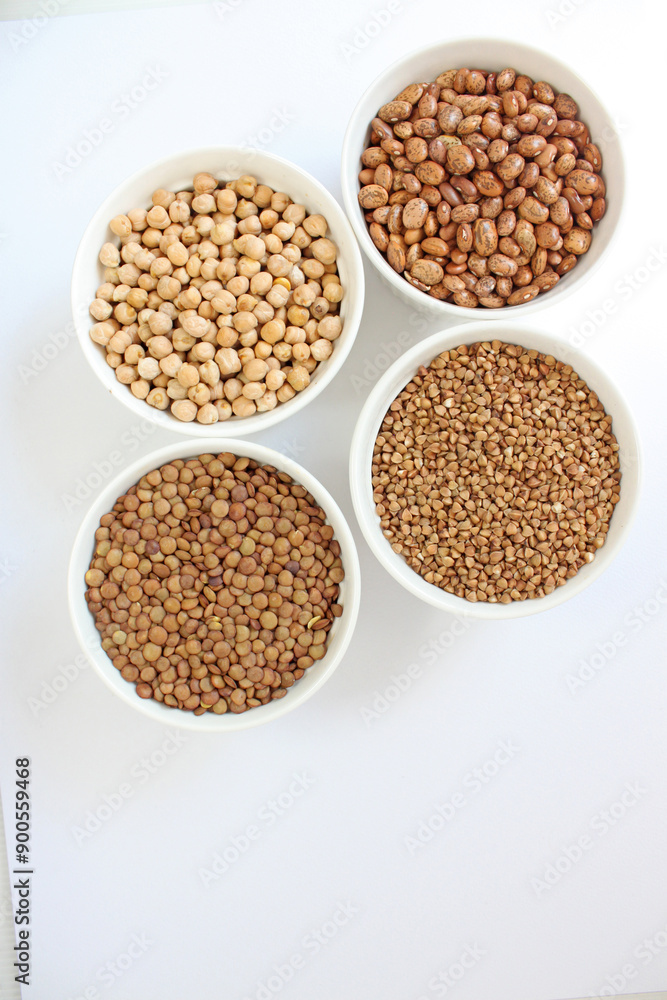 Four white bowls standing on white background, each containing different legume Four white bowls standing on white background, each containing different legume