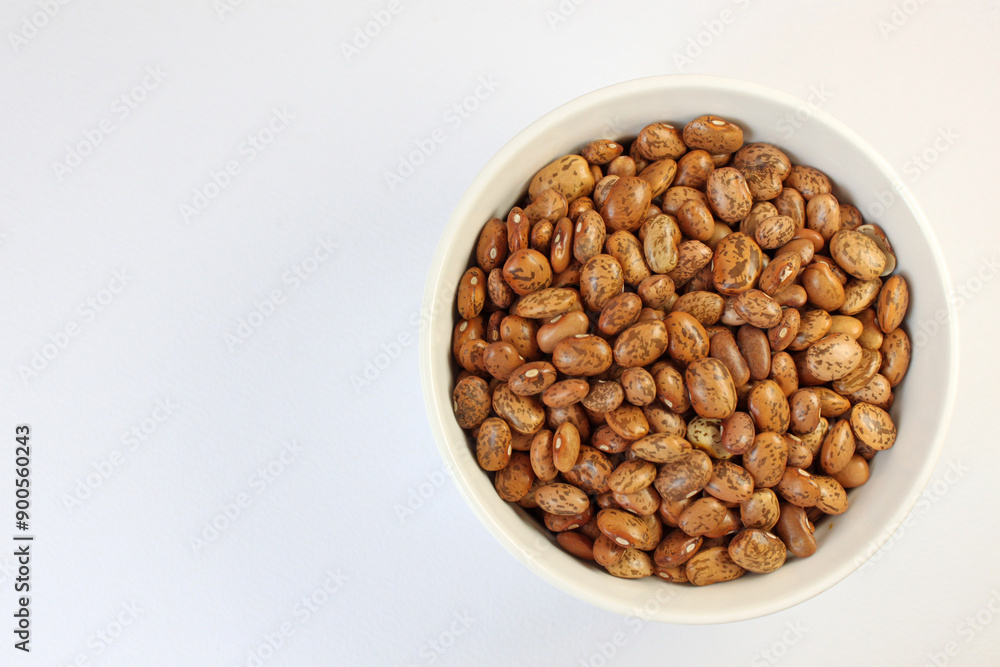 White bowl is overflowing with pinto beans on a white background, perfect for showcasing healthy eating White bowl is overflowing with pinto beans on a white background, perfect for showcasing healthy eating