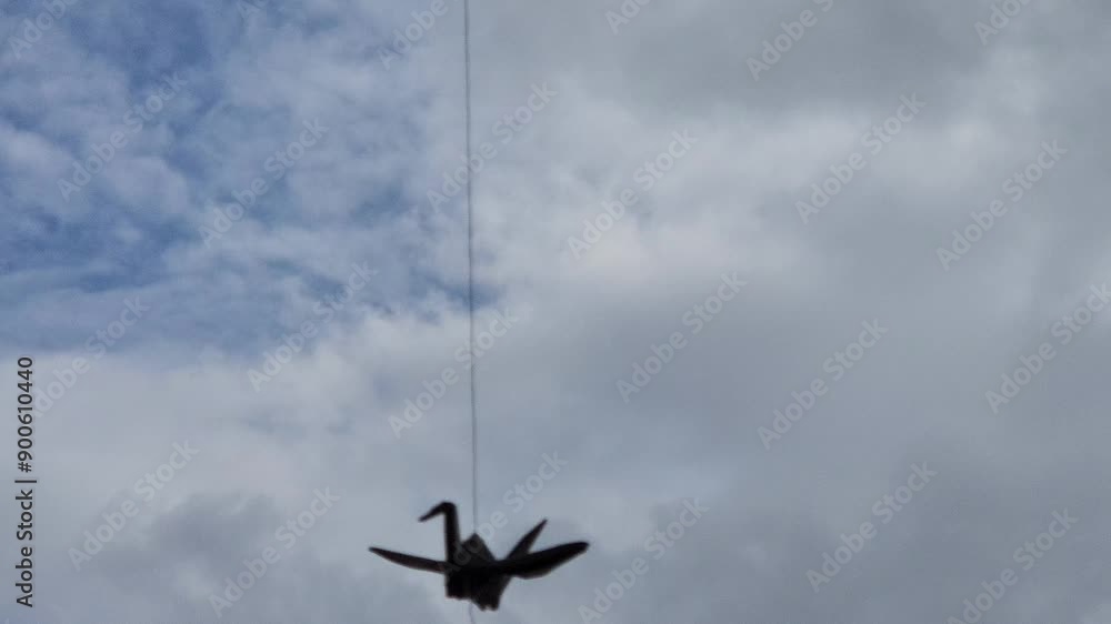 Silhouette of origami crane swinging on the window against the sky. Origami crane is a symbol of happiness and prosperity. paper origami birds-cranes. Silhouette of origami crane swinging on the window against the sky. Origami crane is a symbol of happiness and prosperity. paper origami birds-cranes.
