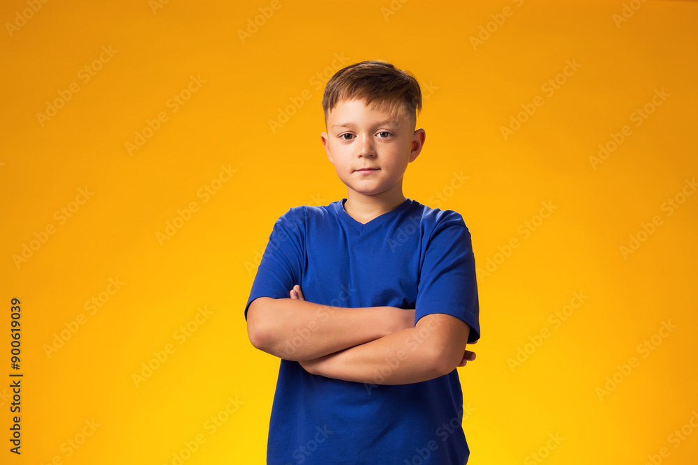 Kid boy looking at camera with crossed hands over yellow background Kid boy looking at camera with crossed hands over yellow background