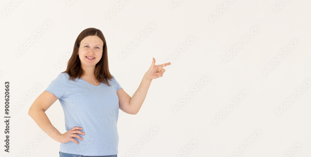 Hey look. Smiling pretty female model pointing finger right at empty space and inviting to check it out, showing advertisement on white background. Hey look. Smiling pretty female model pointing finger right at empty space and inviting to check it out, showing advertisement on white background.
