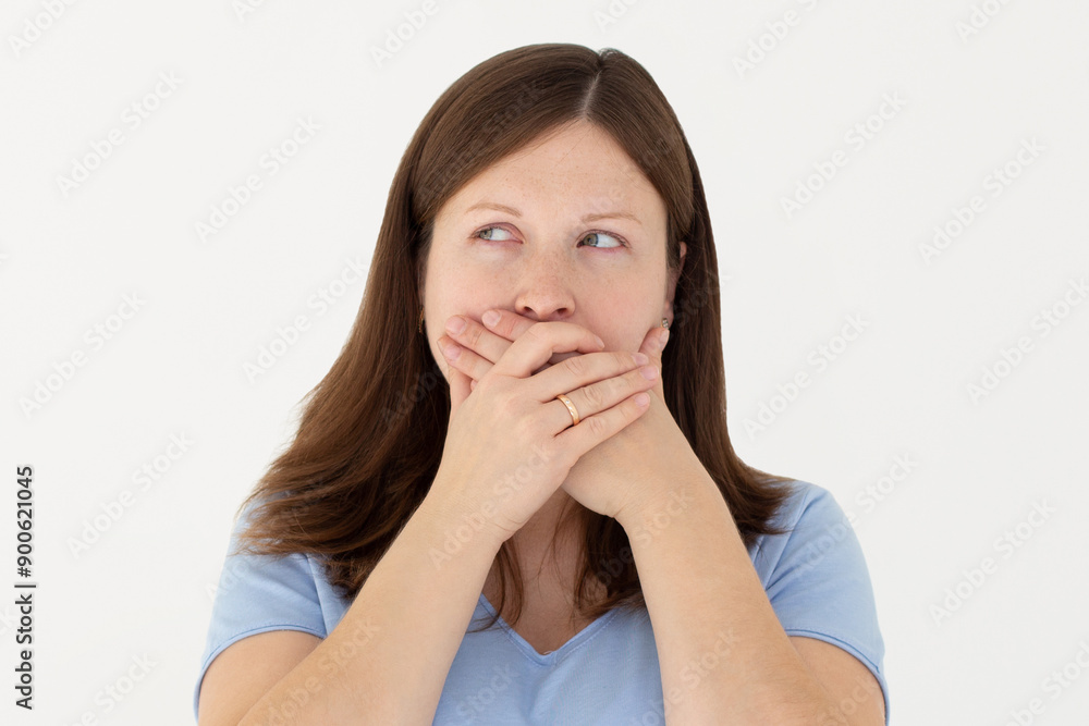 Portrait of a shocked young girl in blue t-shirt looking aside with mouth covered isolated over white background Portrait of a shocked young girl in blue t-shirt looking aside with mouth covered isolated over white background