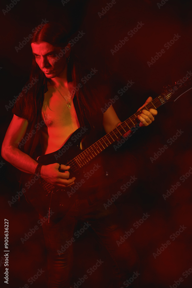 Obraz premium Long-haired Electric Guitarist Playing Under Red Light