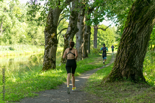 Rear view on active young woman running during the triathlon competition.