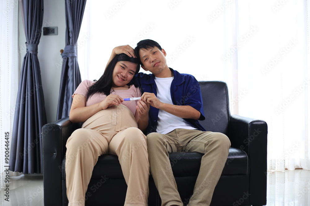 Happy man with pregnant wife rubbing his belly while relaxing and spending time in modern apartment. Pregnant woman and husband spending time together using smartphone Happy man with pregnant wife rubbing his belly while relaxing and spending time in modern apartment. Pregnant woman and husband spending time together using smartphone