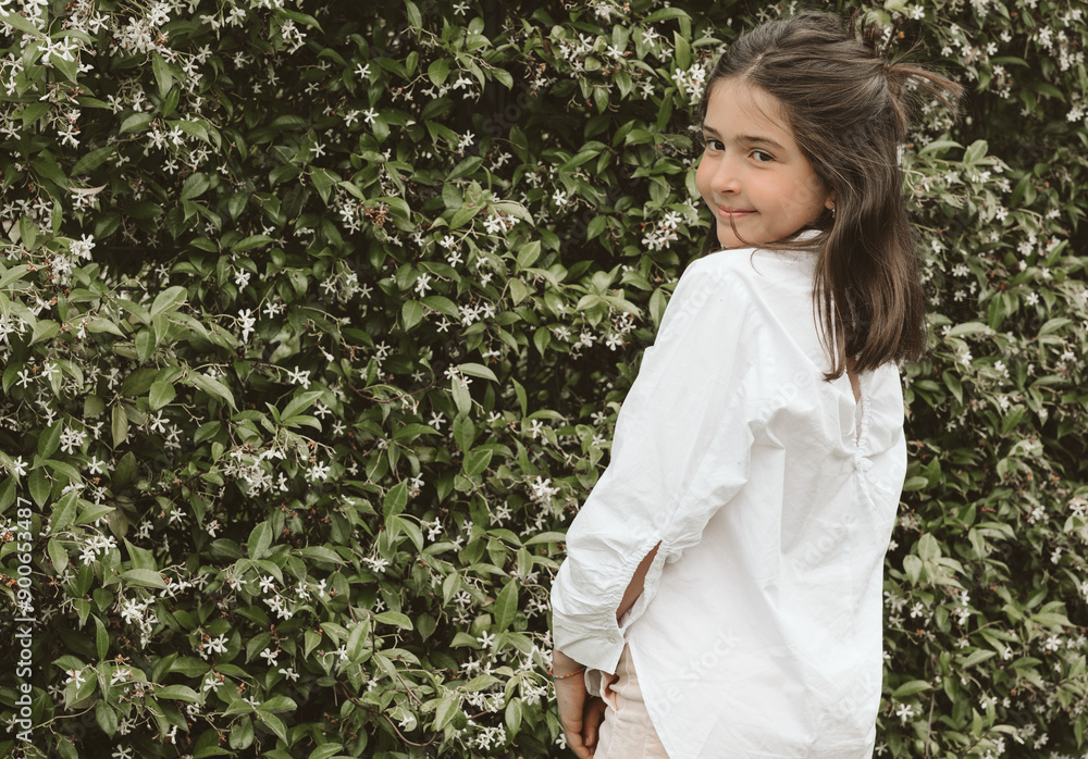 Smiling young girl posing backwards in the garden, copy space Smiling young girl posing backwards in the garden, copy space