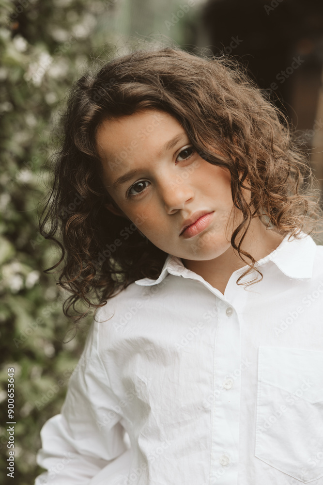 Close-up portrait of a serious young girl with curly hair in the garden Close-up portrait of a serious young girl with curly hair in the garden