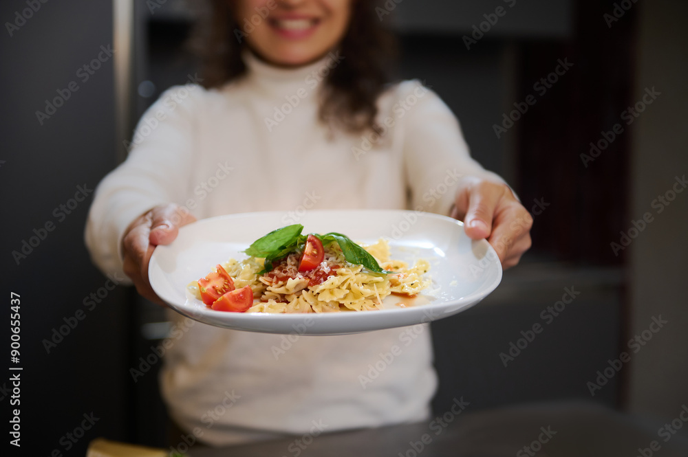Smiling woman presenting a delicious plate of pasta with fresh tomatoes and basil Smiling woman presenting a delicious plate of pasta with fresh tomatoes and basil