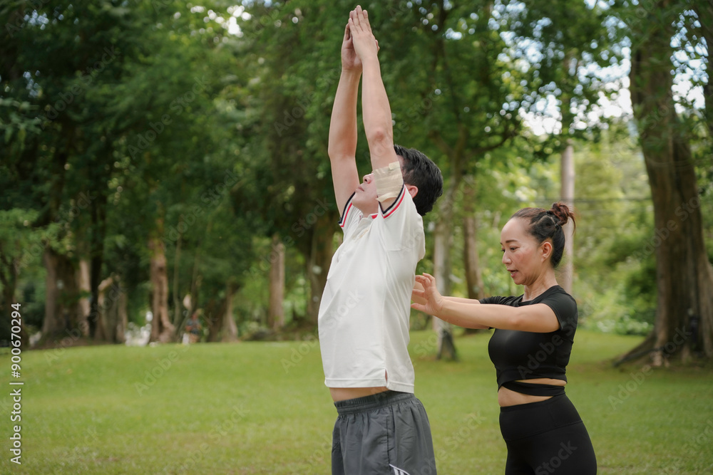 Yoga instructor is correcting the posture of a man practicing yoga in a lush green park Yoga instructor is correcting the posture of a man practicing yoga in a lush green park