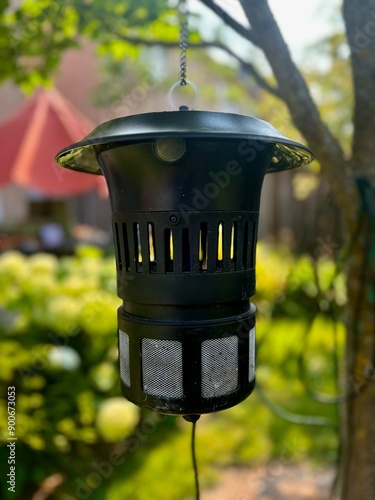Tableau sur toile A bug Zapper hangs from a tree outside, and attracts bugs, insects and mosquitoes using a purple light in the centre of the zapper