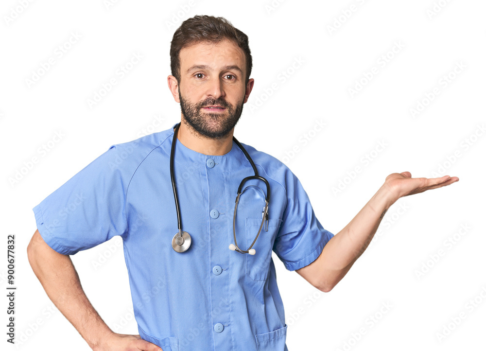 Hispanic male nurse in studio showing a copy space on a palm and holding another hand on waist. Hispanic male nurse in studio showing a copy space on a palm and holding another hand on waist.