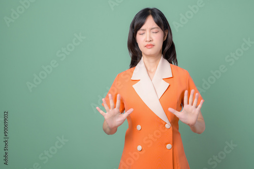 Fotografie Woman in an orange dress closing her eyes in discomfort or rejection, with her h