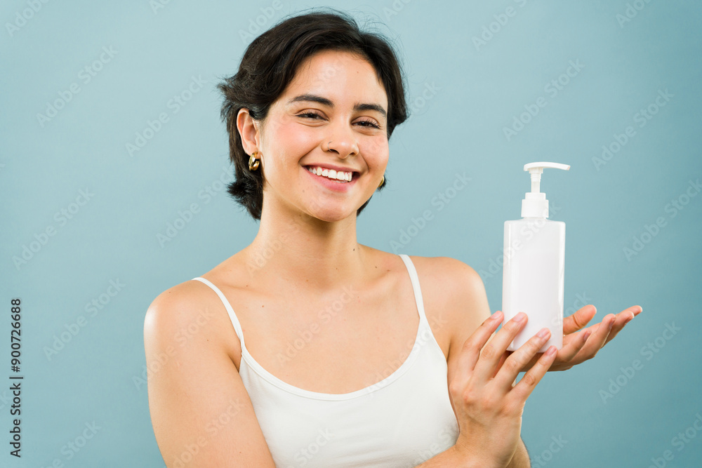 Young woman happily holding a white plastic bottle with a dispenser pump for beauty products Young woman happily holding a white plastic bottle with a dispenser pump for beauty products