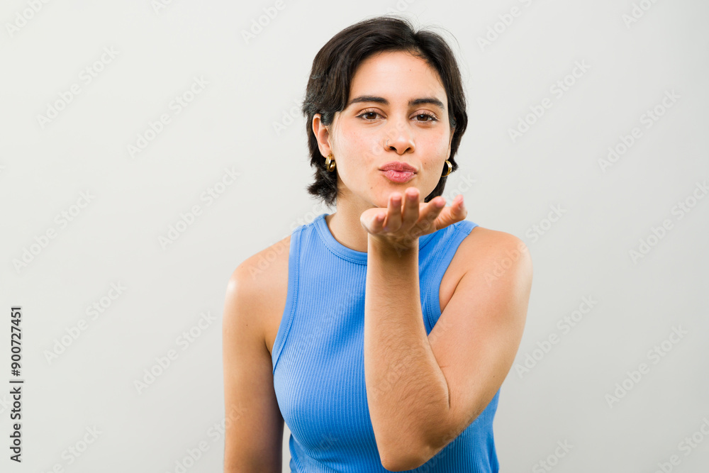 Stylish young brunette woman in a chic blue shirt playfully blows a kiss, exuding confidence and grace Stylish young brunette woman in a chic blue shirt playfully blows a kiss, exuding confidence and grace