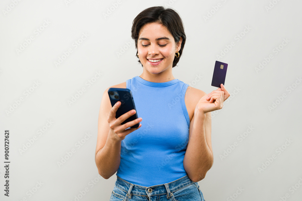 Happy young woman holding credit card and using smartphone for online shopping at home Happy young woman holding credit card and using smartphone for online shopping at home