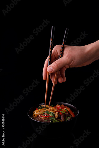 Stir fry noodles with vegetables and shrimps in black bowl. Slate background. Top view. Copy space.