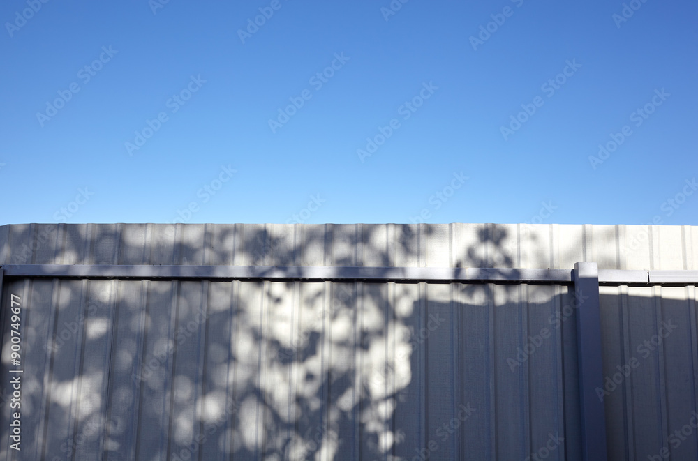 Corrugated steel fence against blue sky. Corrugated metal texture surface or galvanize steel Corrugated steel fence against blue sky. Corrugated metal texture surface or galvanize steel