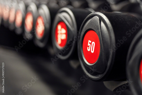 Sports equipment in gym. Dumbbells of different weight close up. Line of disk barbells on a rack for weightlifting and workout.