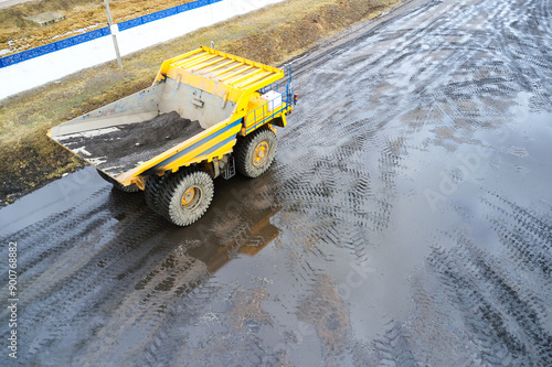 Yellow dump truck with remote control works in a dirty quarry photo