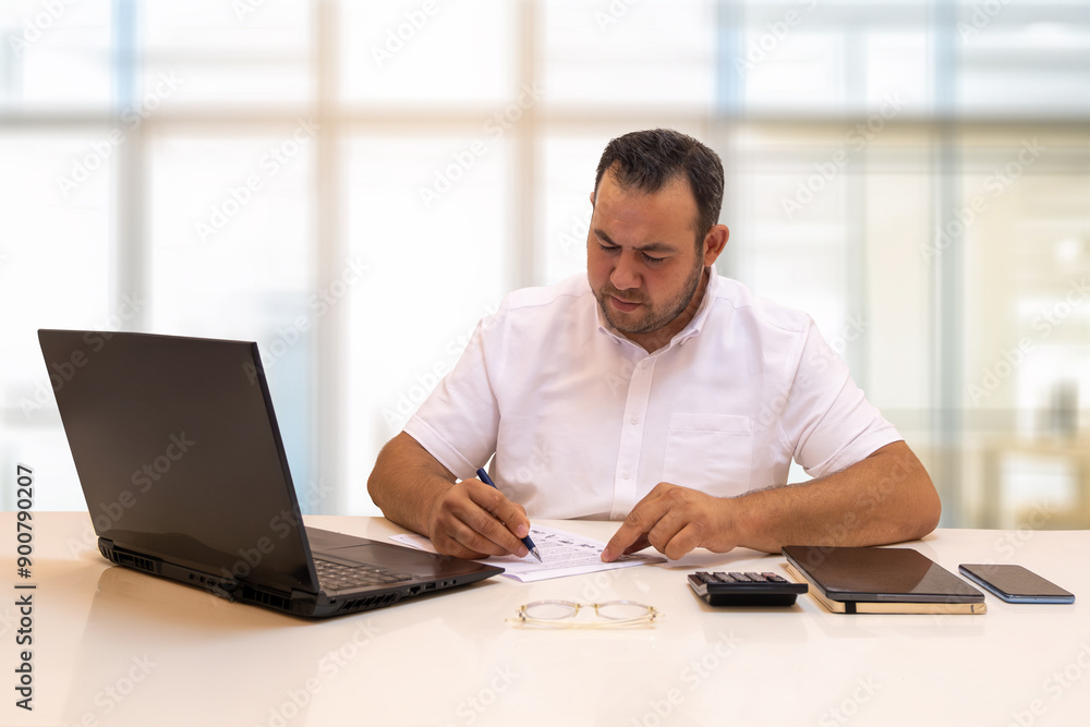 Businessman taking notes with his eyebrows furrowed. With the reflection of his busy work life Businessman taking notes with his eyebrows furrowed. With the reflection of his busy work life