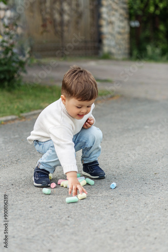 Toddler Boy Playing with Chalk on Pavement © Olha Tsiplyar