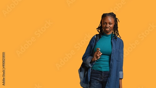 Foto Anxious student at school thinking of raising arm to answer question but unsure of herself, studio background